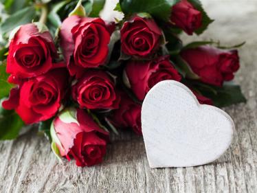 Strauß mit roten Rosen und weißem Holzherz davor